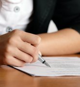 Frauenhand schreibt auf einem Blatt Papier