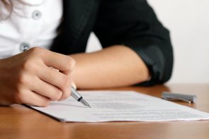Frauenhand schreibt auf einem Blatt Papier