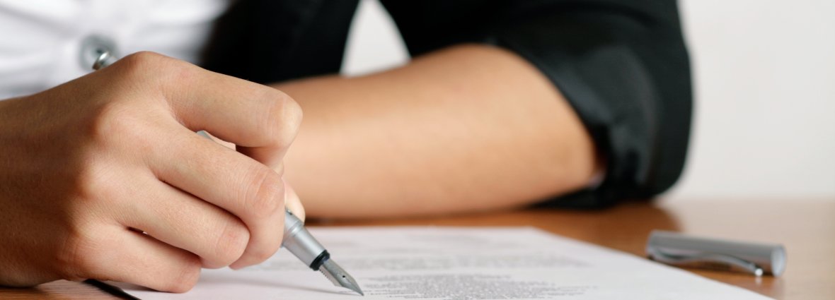 Frauenhand schreibt auf einem Blatt Papier