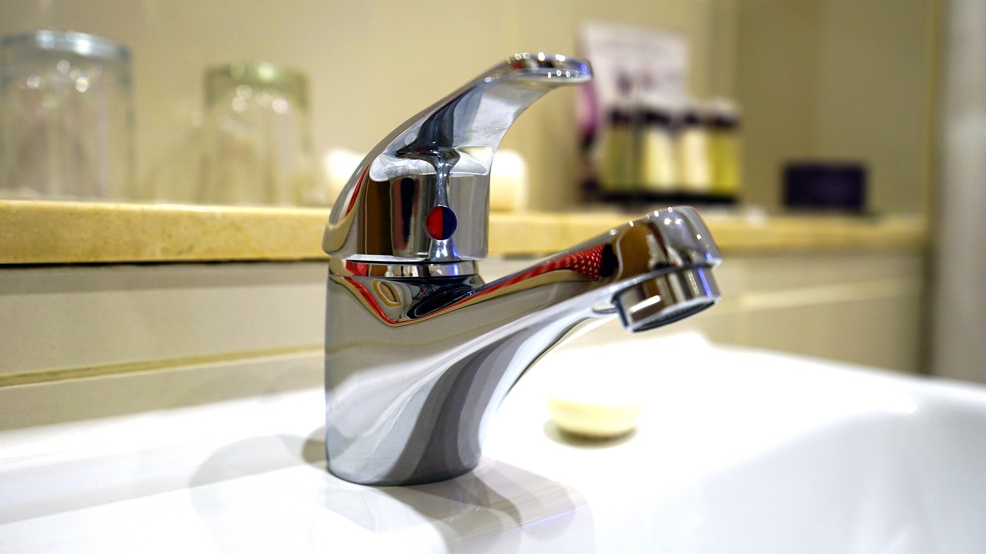Wasserhahn mit Trinkgläsern im Hintergrund
