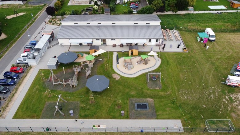 Die Kita Wichtelwiese von oben. Mit dem Kindergartengebäude und dem neu gestalteten Außengelände mit viel Grün und verschiedenen altersgerechten Spielgeräten