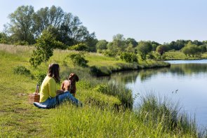 Frau mit Hund am Seeufer des Bergwerksees in Dorn-Assenheim