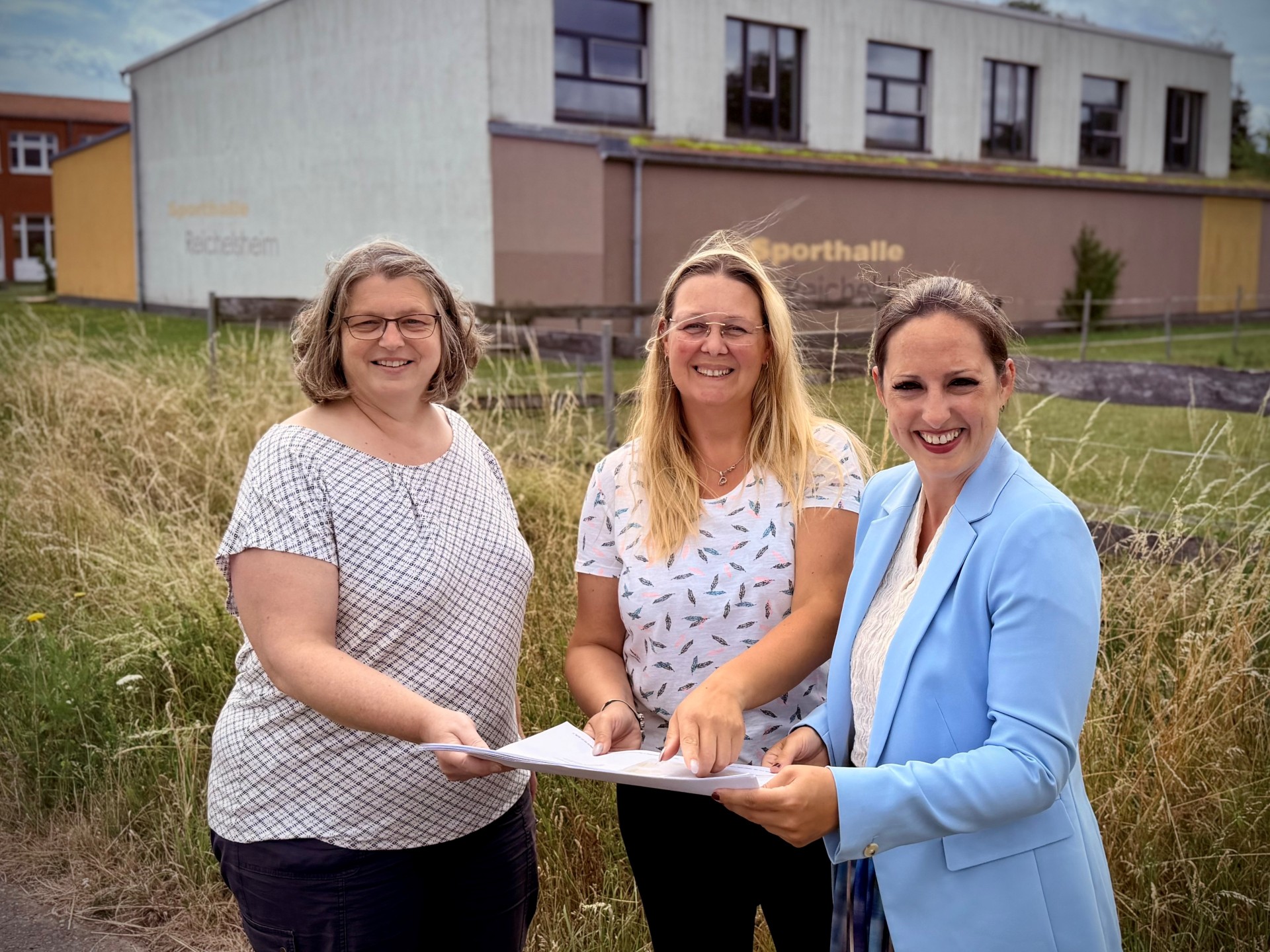 Bauamtsleiterin Petra Klöppel, Kita-Leiterin Corina Morkel und Bürgermeisterin Lena Herget stehen auf dem Baugrundstück der neuen Kita in Reichelsheim