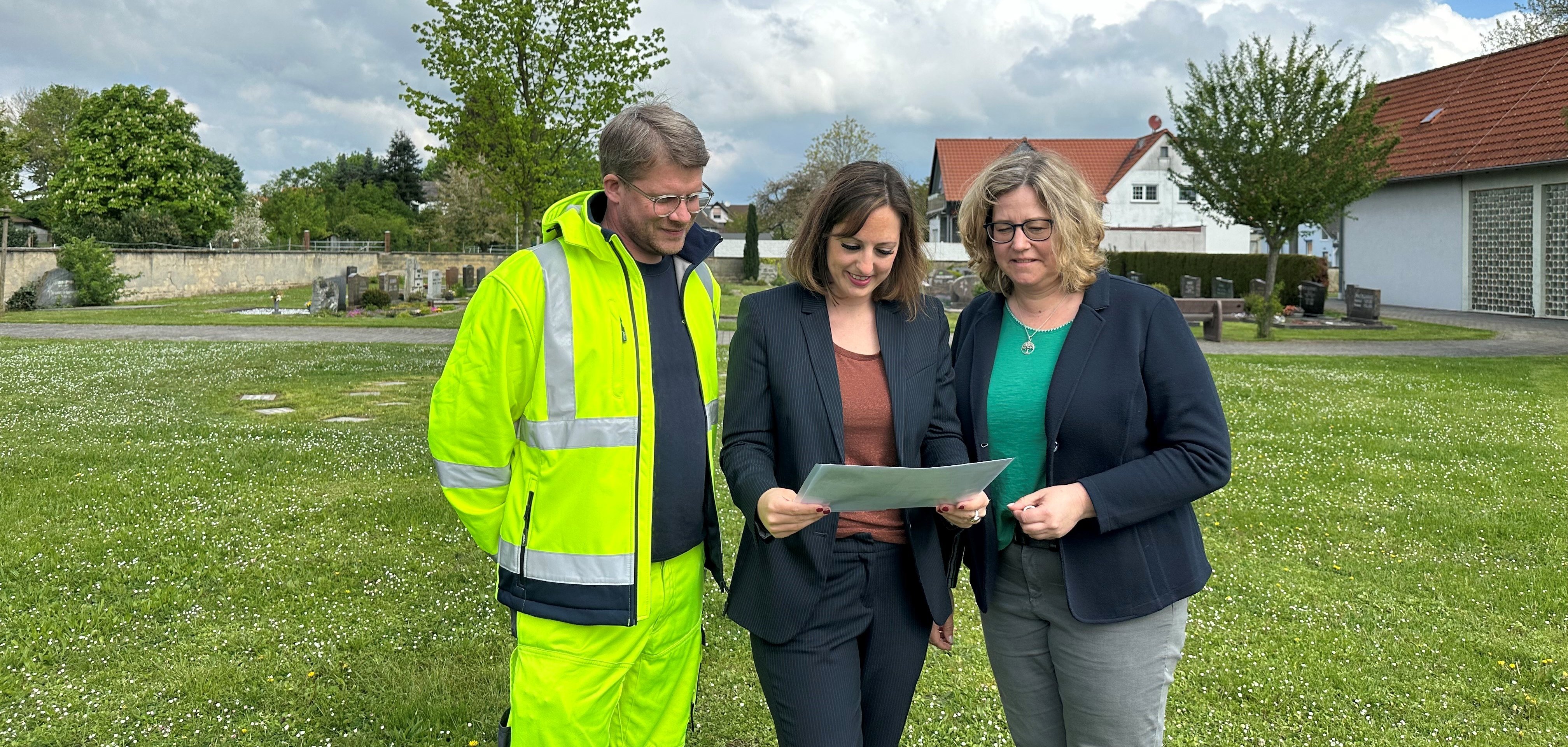 Nils Tolksdorf (Bauhofleiter), Bürgermeisterin Lena Herget und Miriam Euler (Friedhofsverwaltung) auf dem Friedhof in Reichelsheim