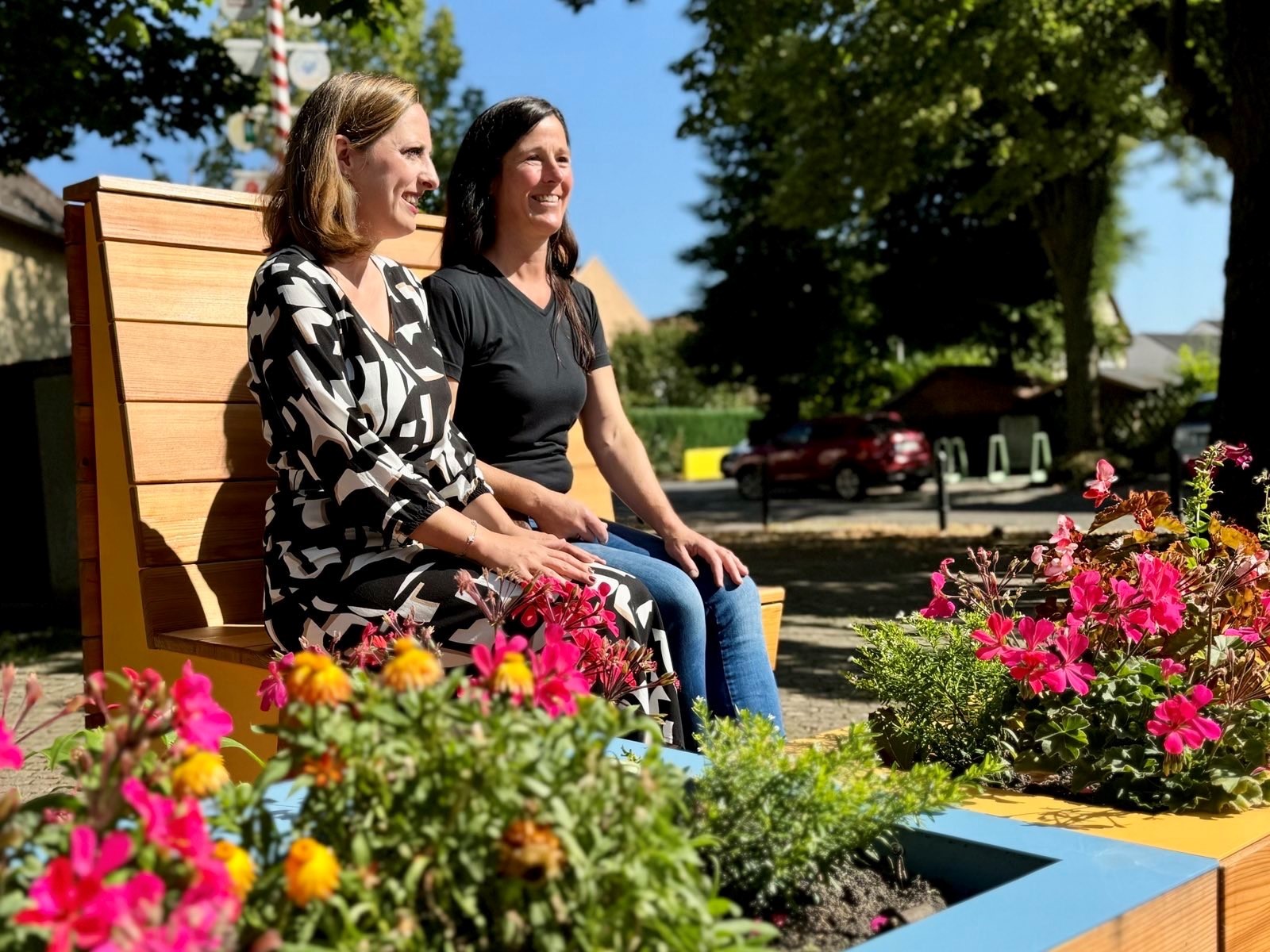 Bürgermeisterin Lena Herget und Sandra Sibbe von der „Alten Blechwerkstatt“ genießen die neuen Stadtmöbel in Weckesheim